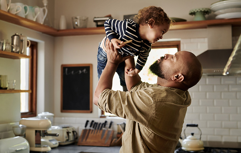 father holding his kid up in the kitchen