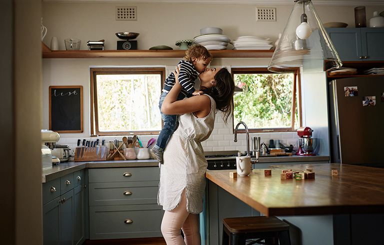 mom holding her son up in the kitchen