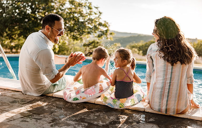 family sitting at the edge of a pool having fun