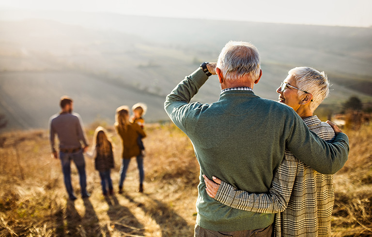 elderly couple looking out at family members