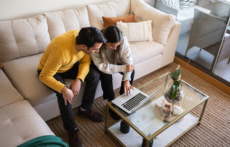 young couple looking at homes on the couch