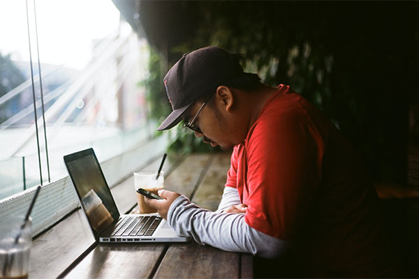 Man with a red shirt at a coffee shop looking at his phone