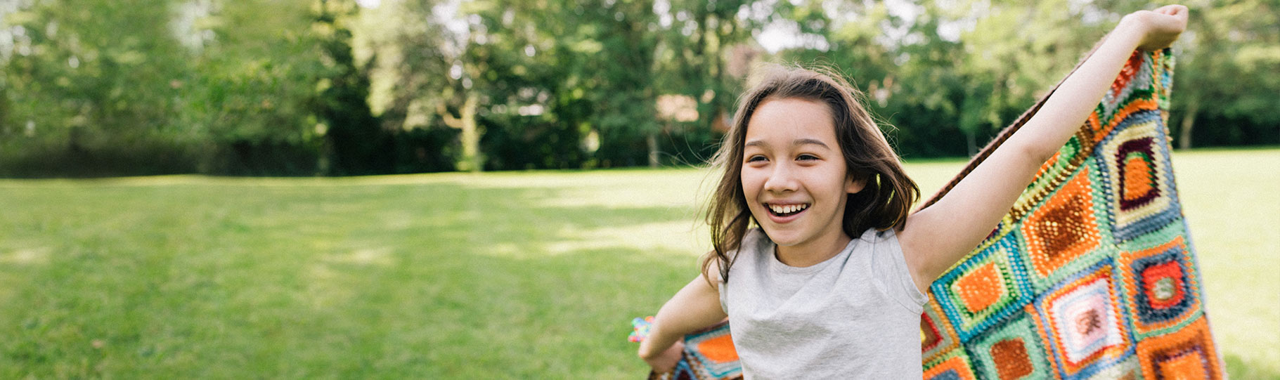 girl smiling using a blanket as a cape