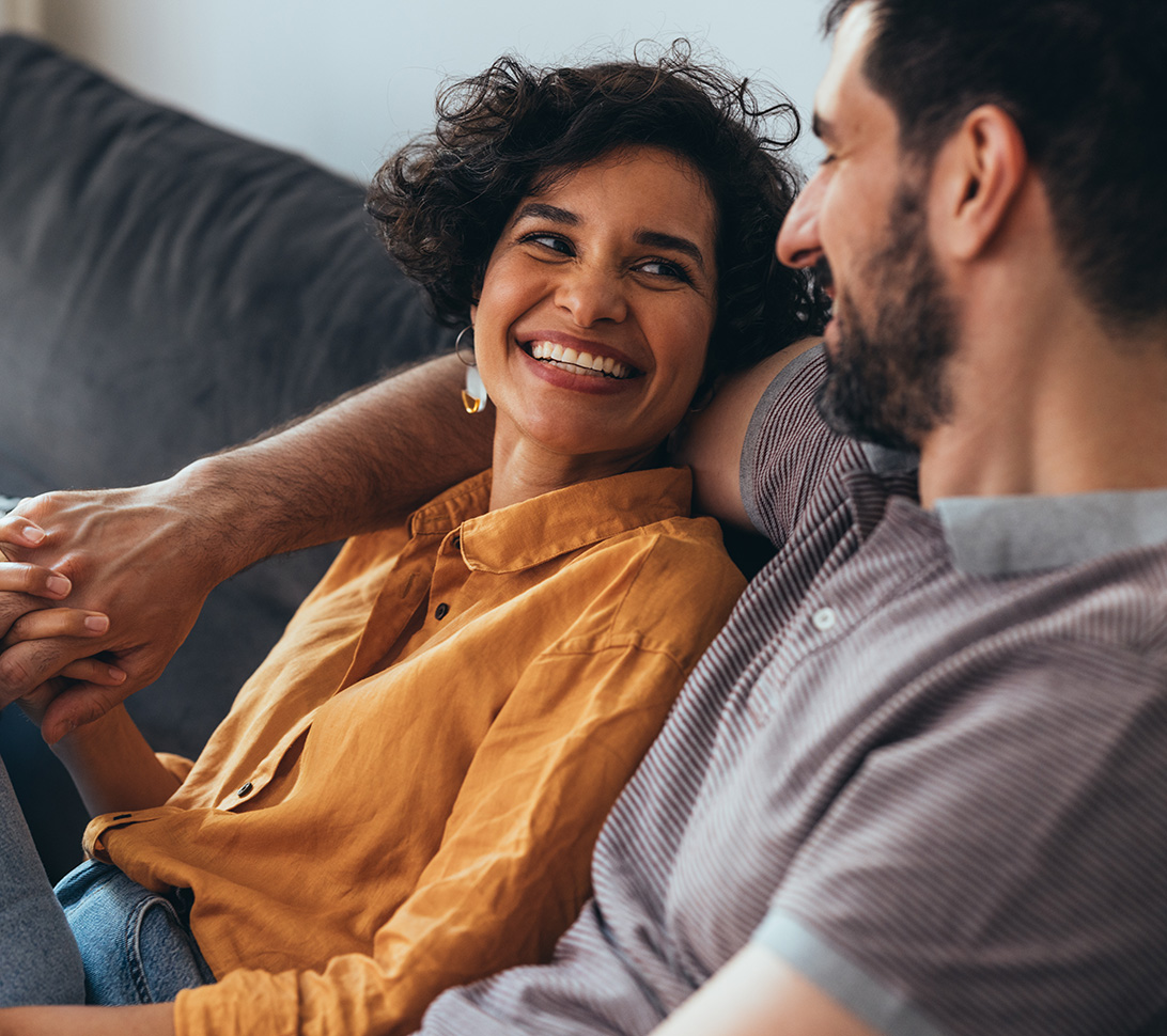 couple smiling and holding hands on the couch