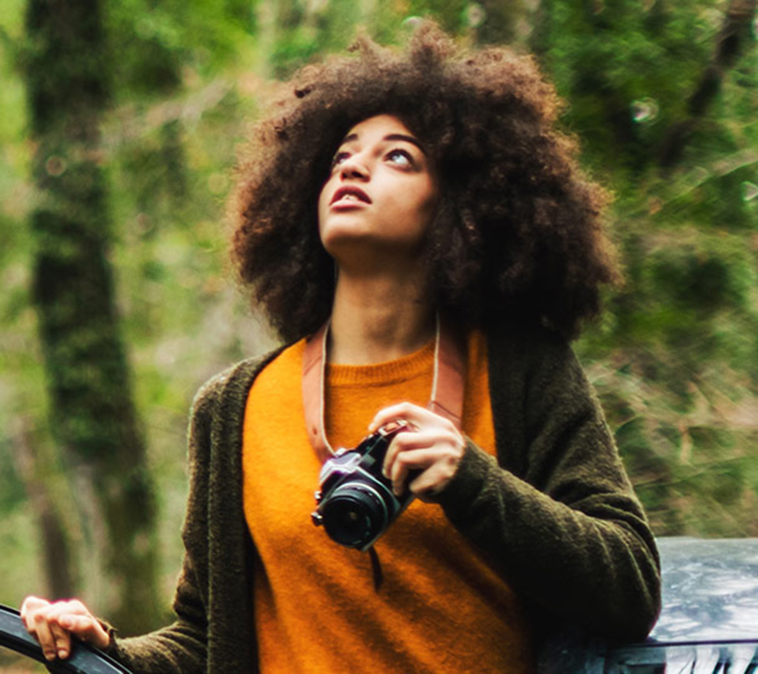 girl holding a camera in the woods