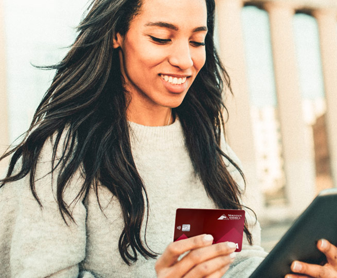 woman holding her Mountain America card and a tablet