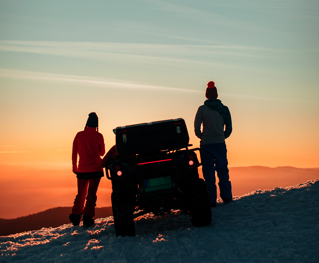 two people standing next to an ATV