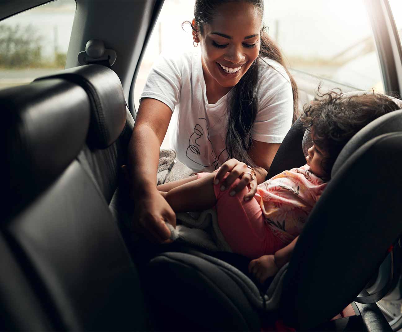 Mother buckling her child into a car seat