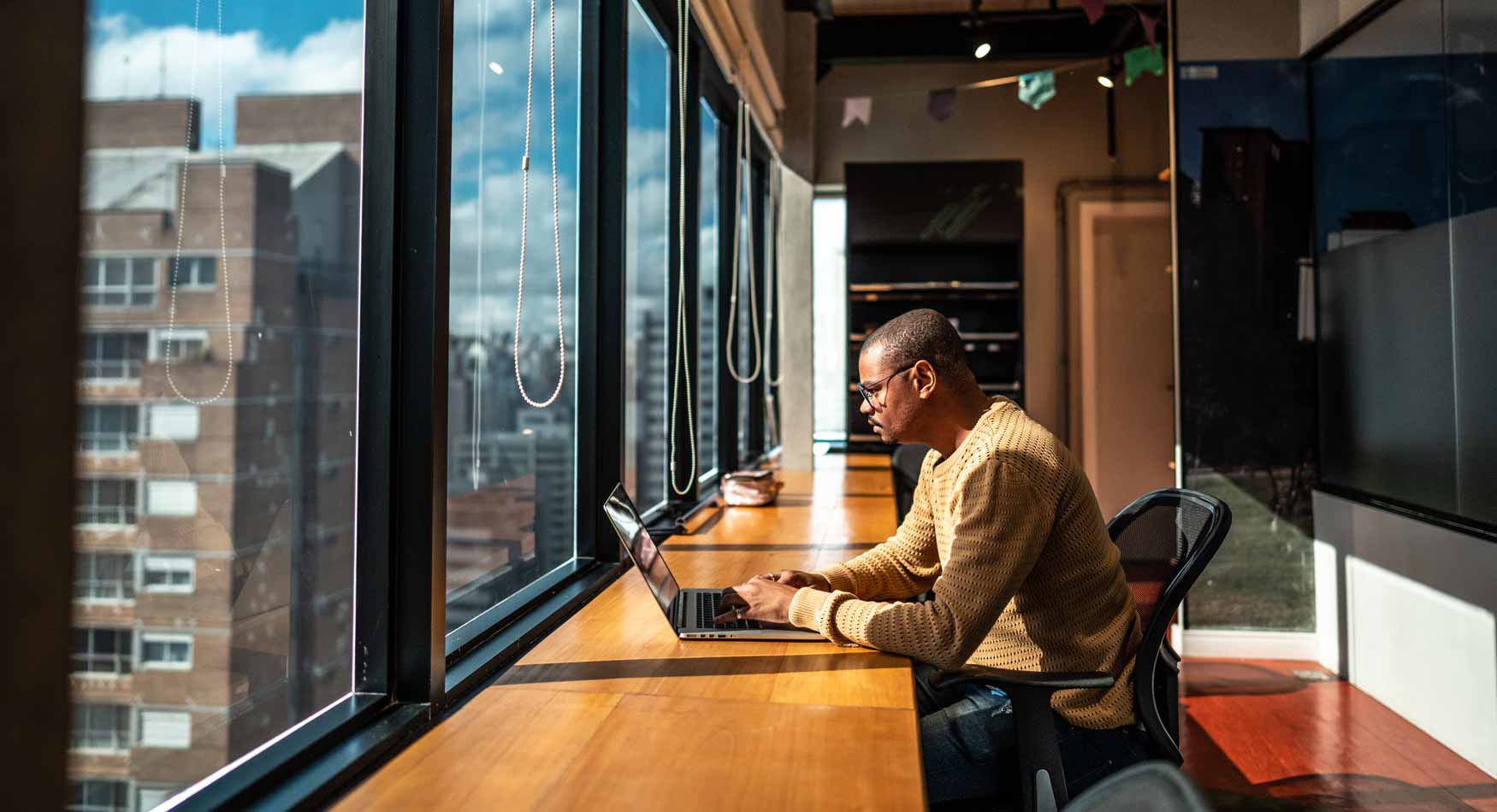 Man working on laptop with city scape view.