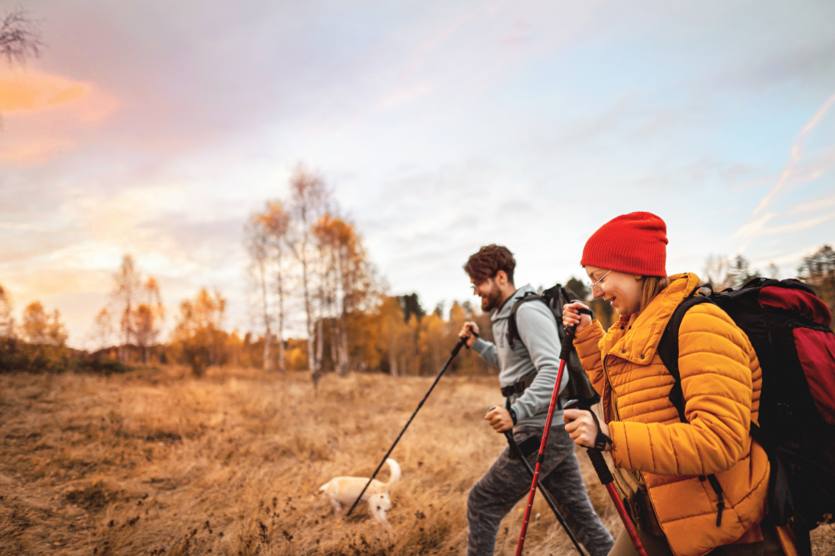 man and woman hiking in autumn with dog