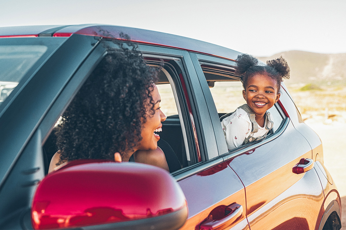 Woman and daughter smiling at each other in windows of new car.