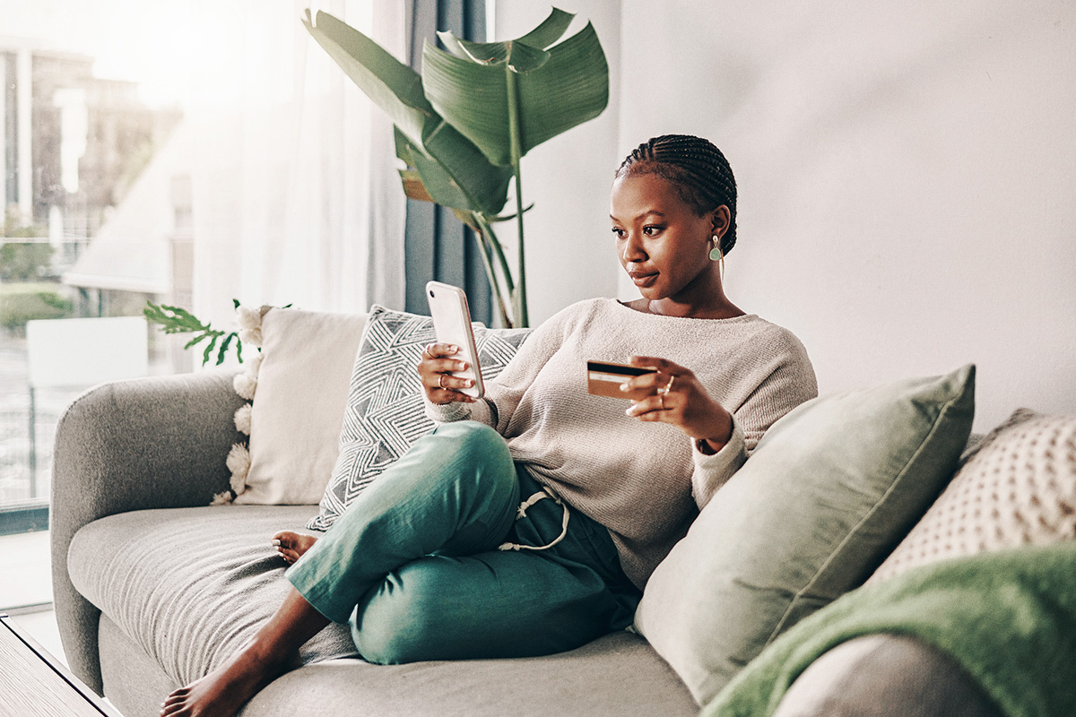 woman sitting on couch with her credit card and mobile phone