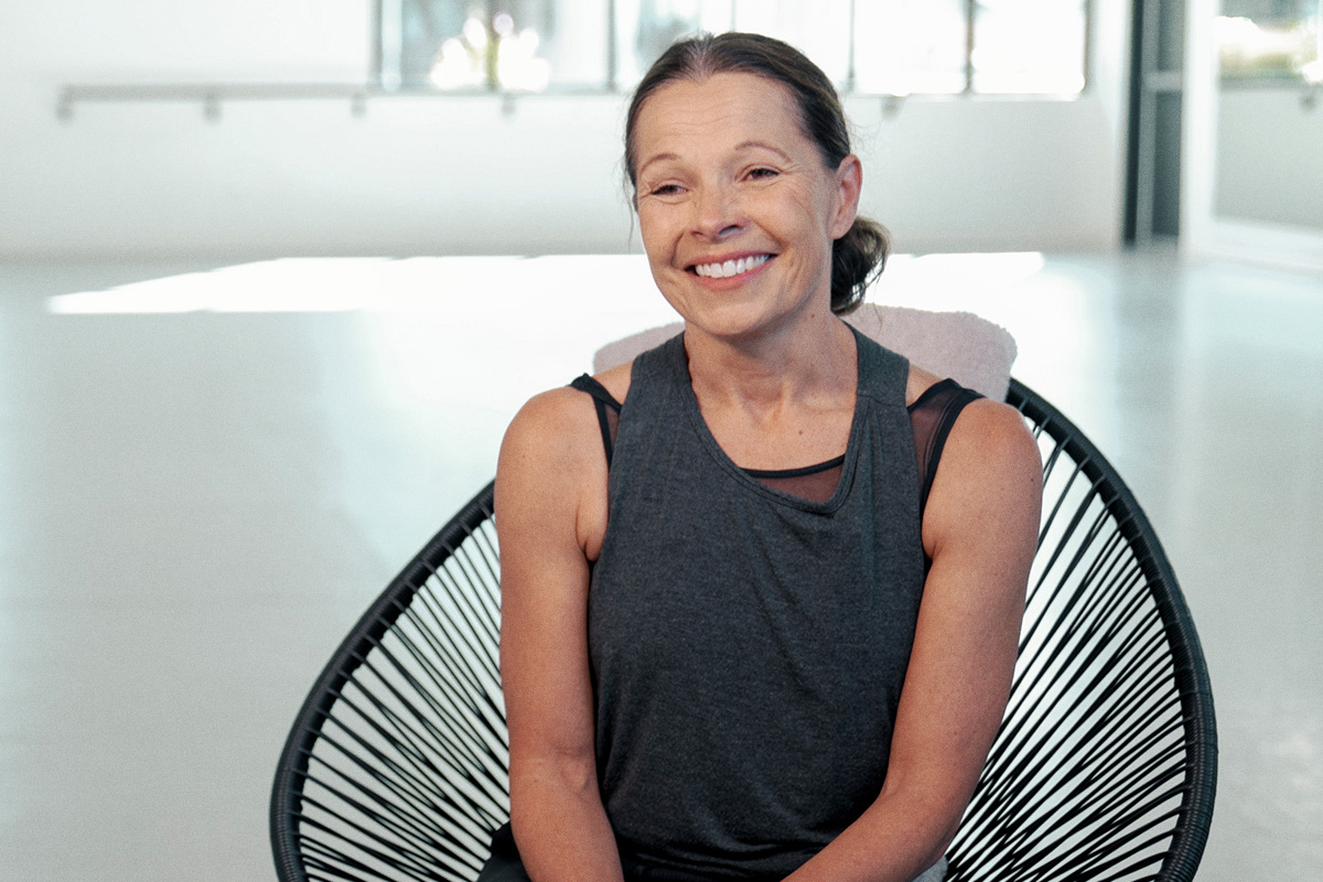 smiling woman sitting in chair in dance studio