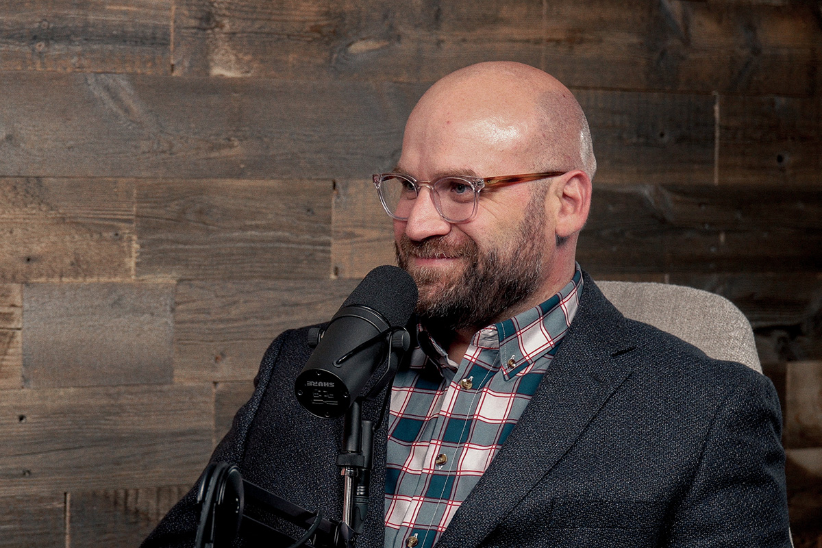 man in glasses and plaid shirt at podcast mic