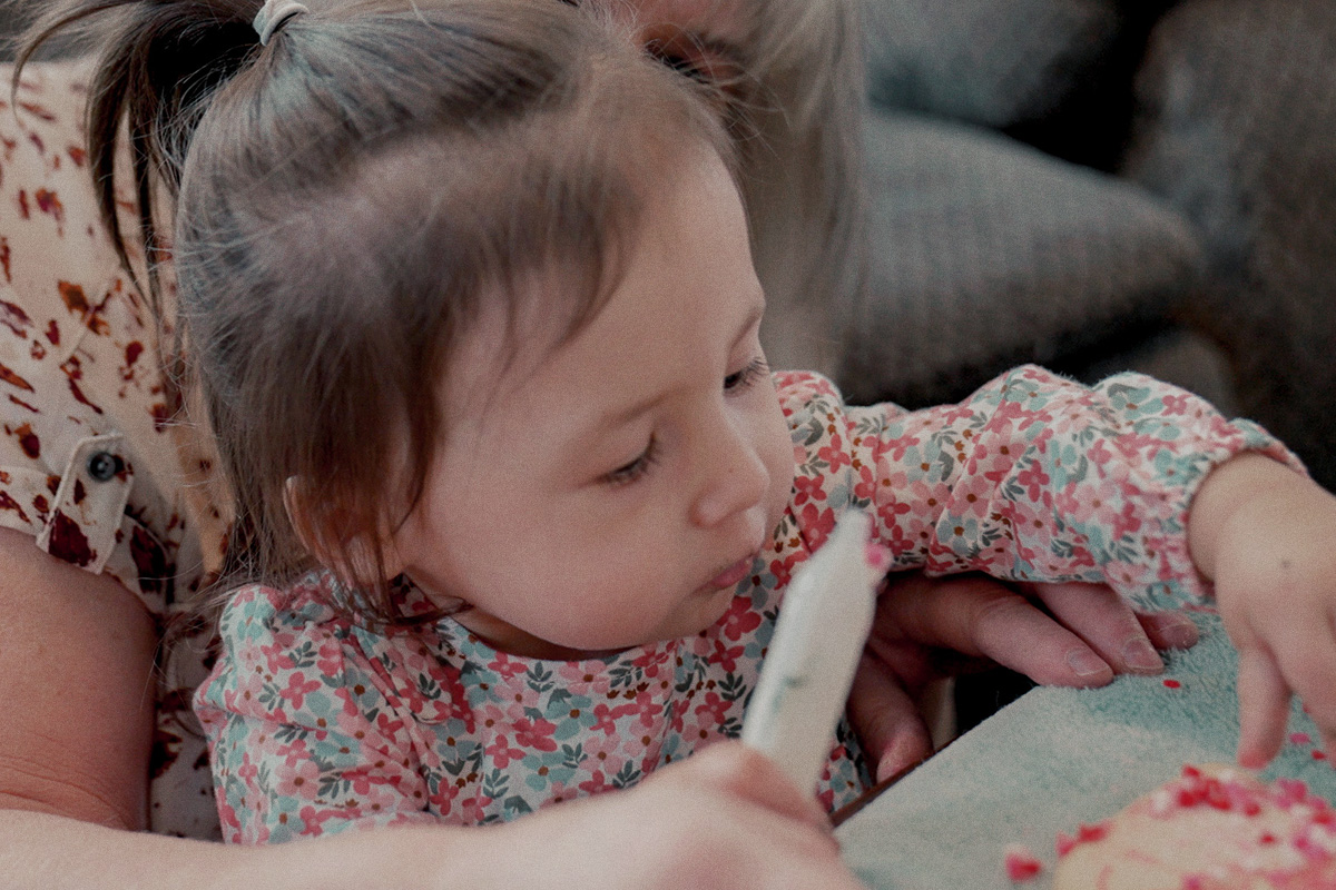 little girl decorating cookies with grandma