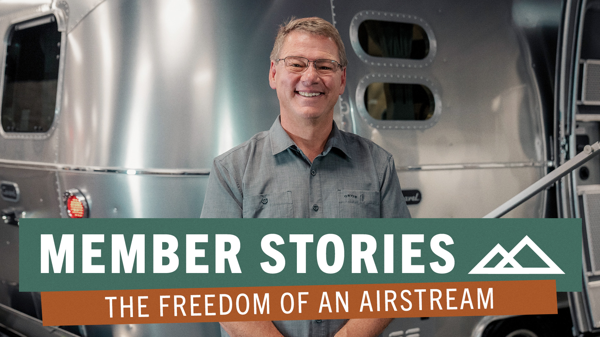 man with glasses standing in front of Airstream trailer