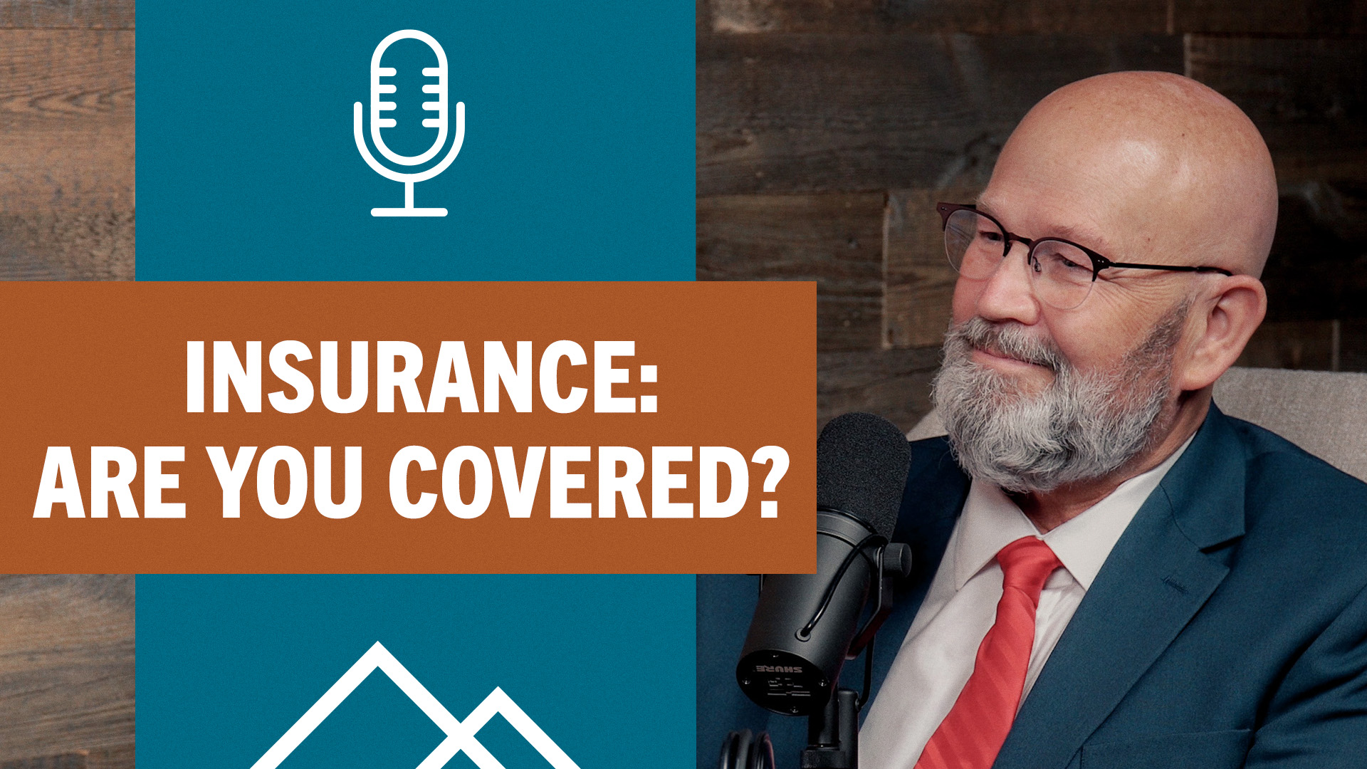 bearded man in glasses with red tie at the podcast mic.