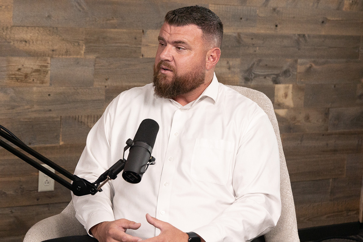 bearded man in white dress shirt at podcast mic