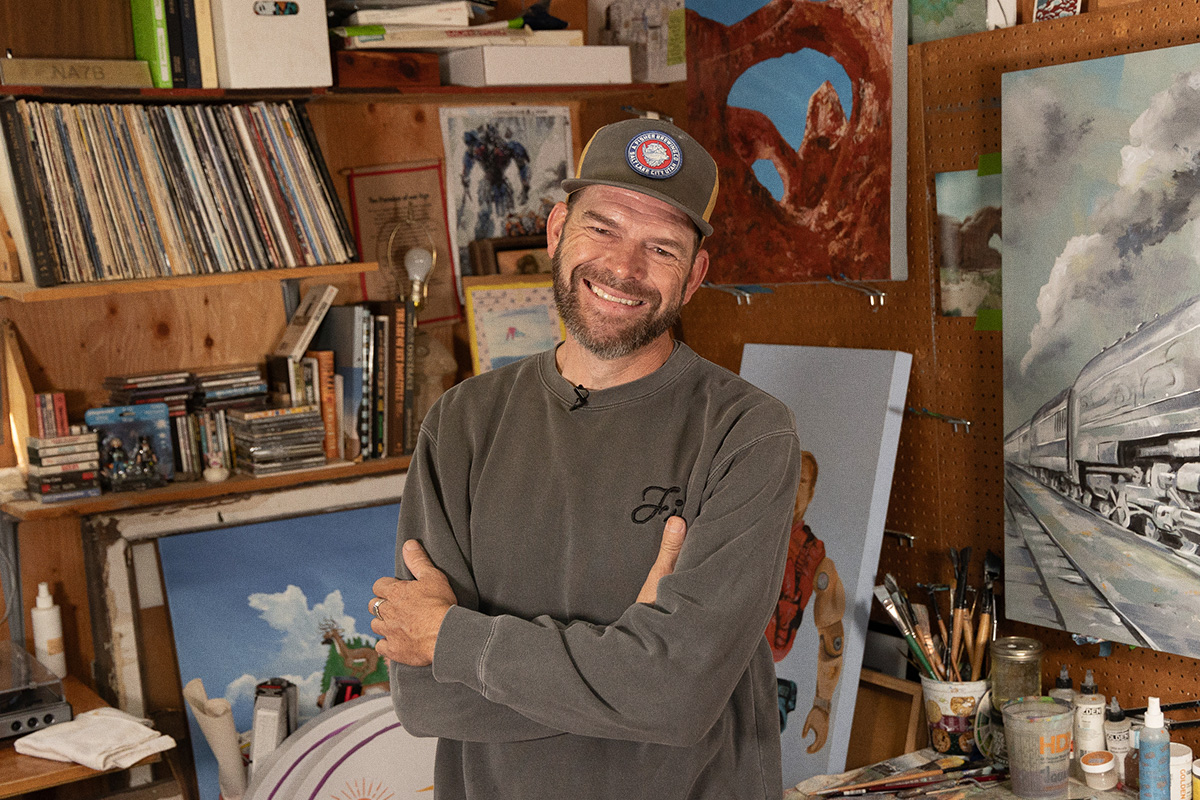 bearded artist standing in studio smiling with arms crossed