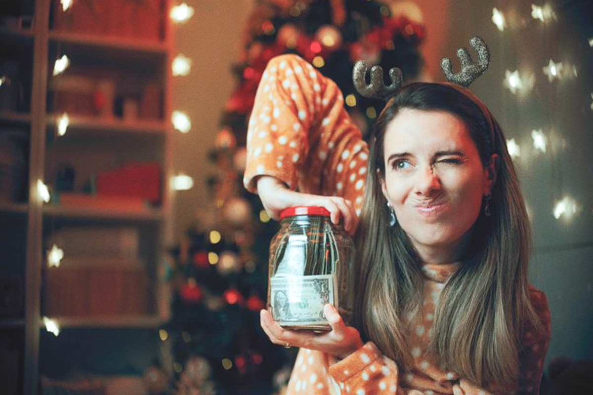 girl with reindeer headband straining to open jar of money