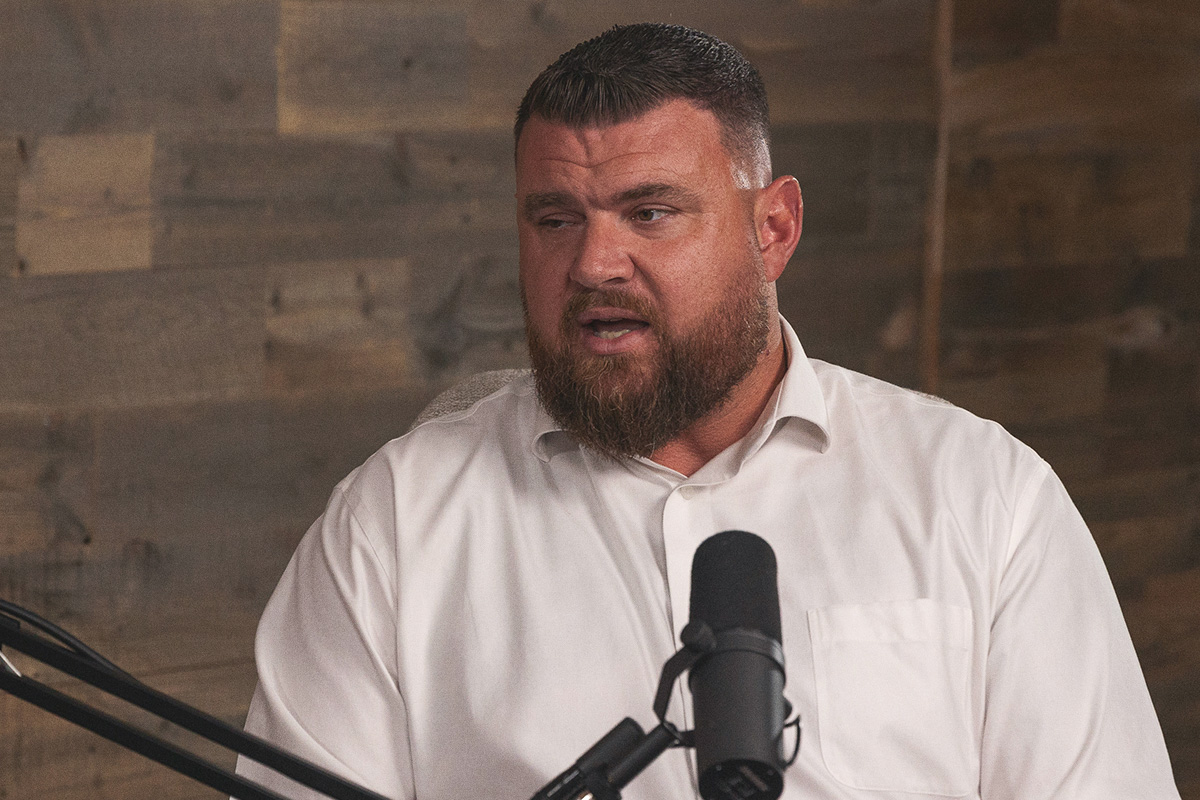 bearded man in white dress shirt at podcast mic