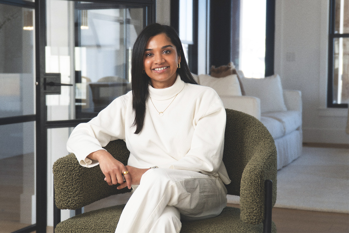 woman in white with long black hair sitting in green chair