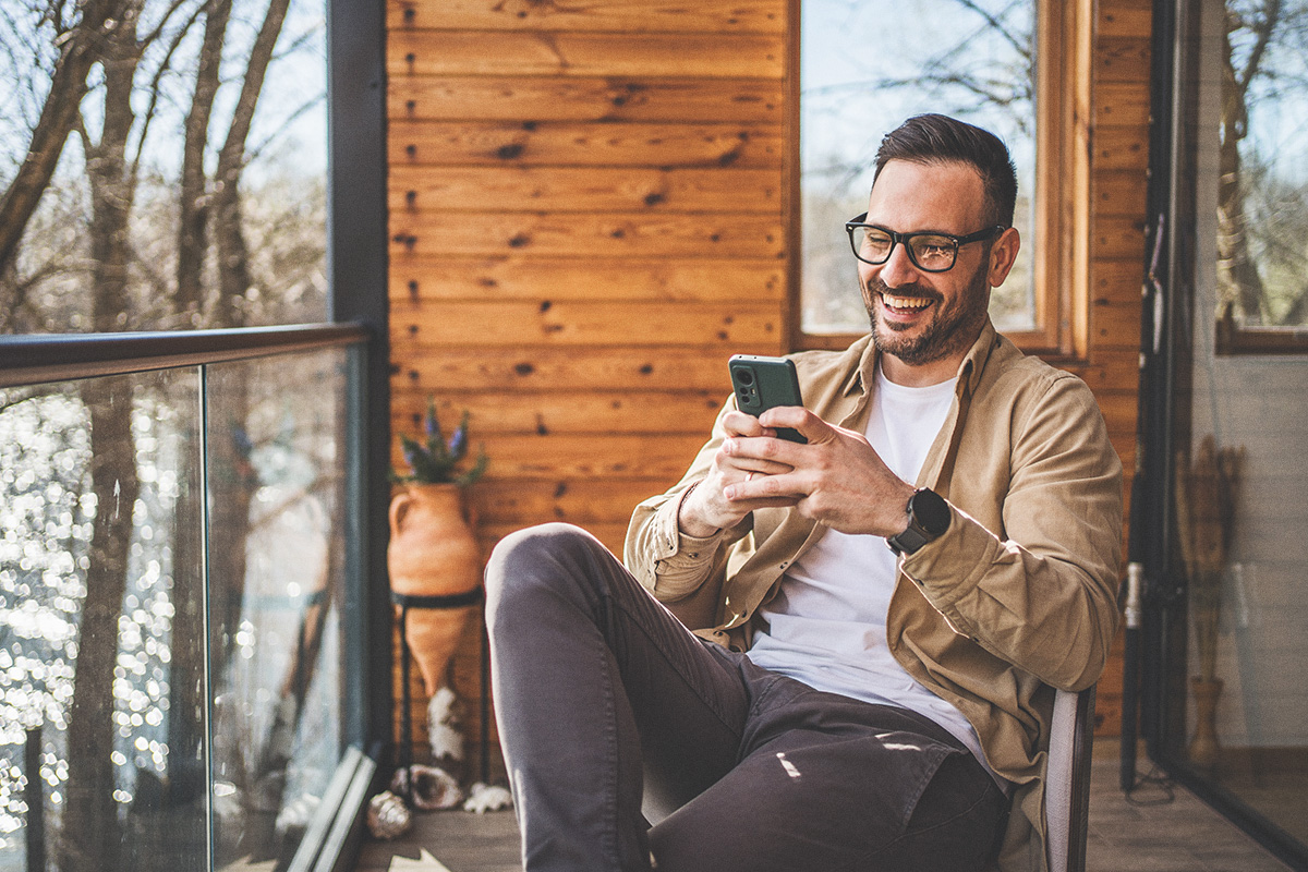 man sitting on rustic porch looking at cell phone