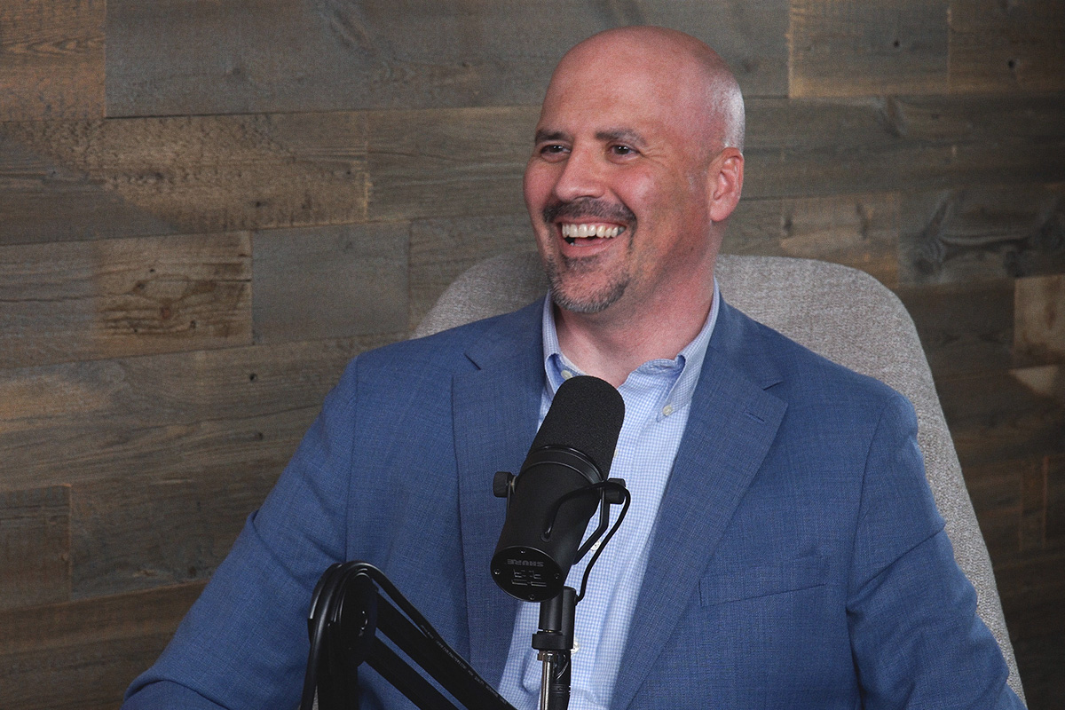 smiling man in blue jacket at the podcast mic