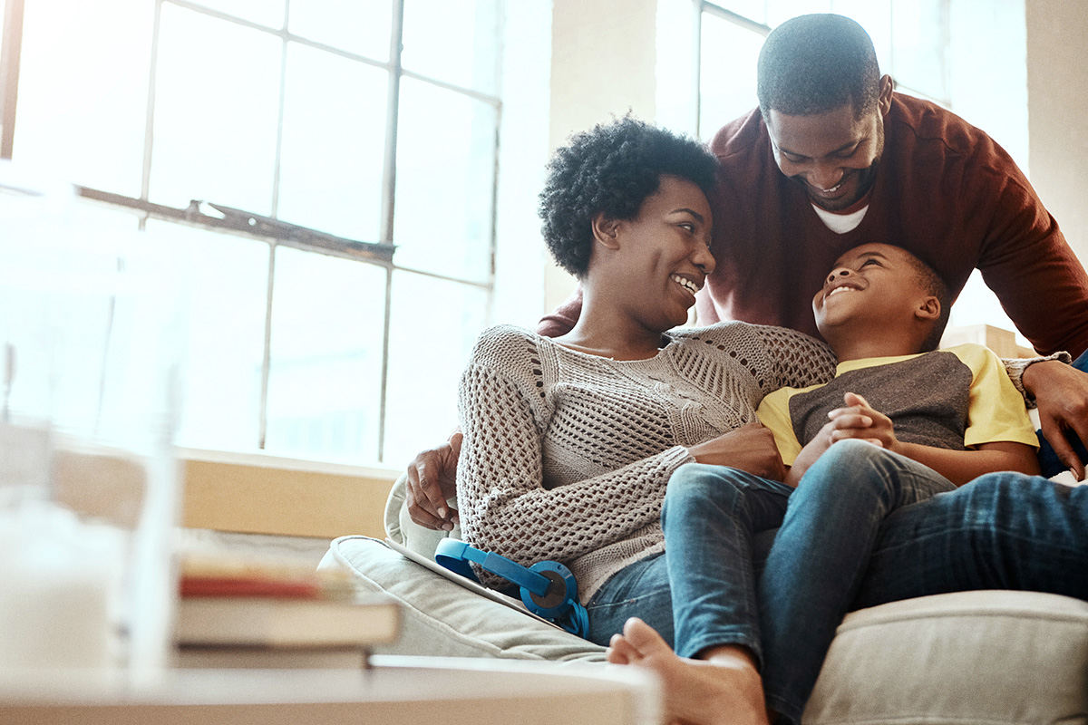 mom, dad and child sitting and laughing on couch