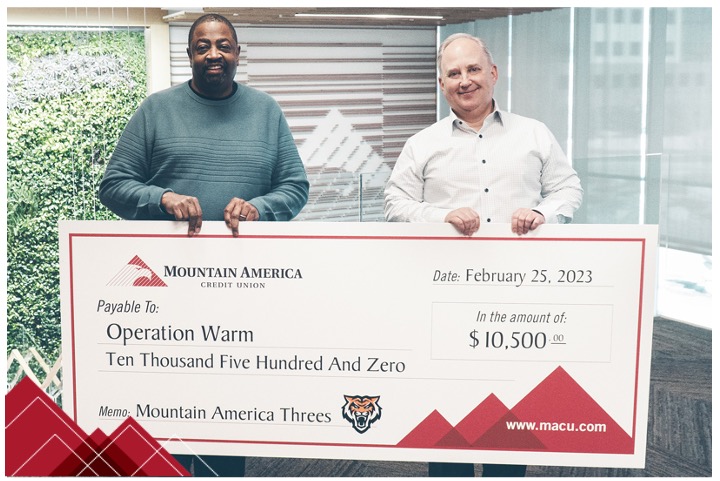 Two people holding a presentation check to Operation Warm