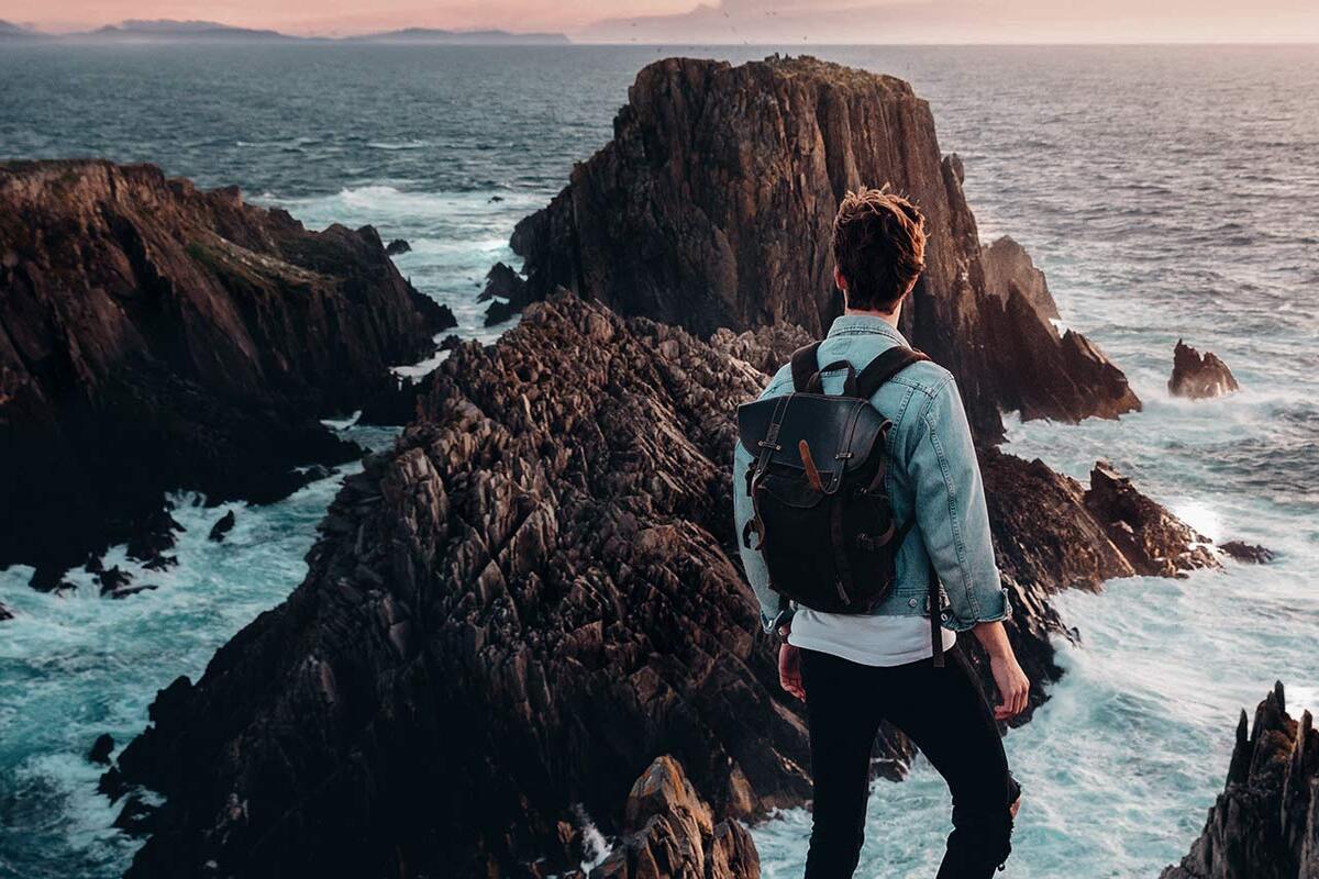 man looking out at rocky structures in the ocean