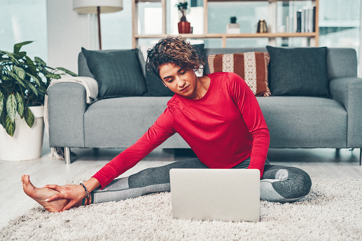 woman stretching while looking at laptop