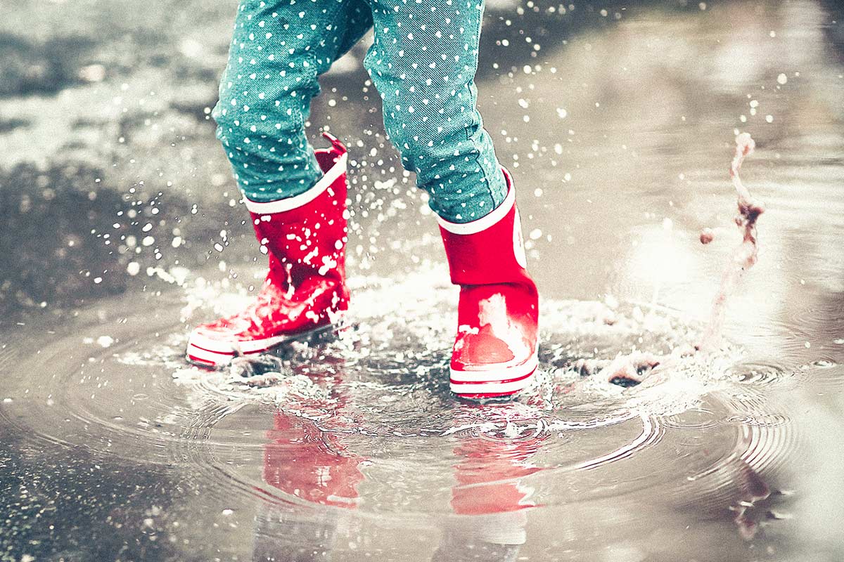 little kid splashing in a puddle