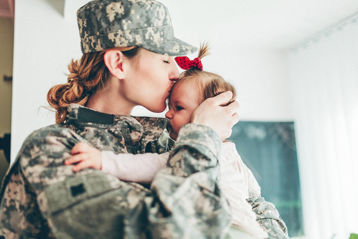 military mom kissing her baby on the forehead