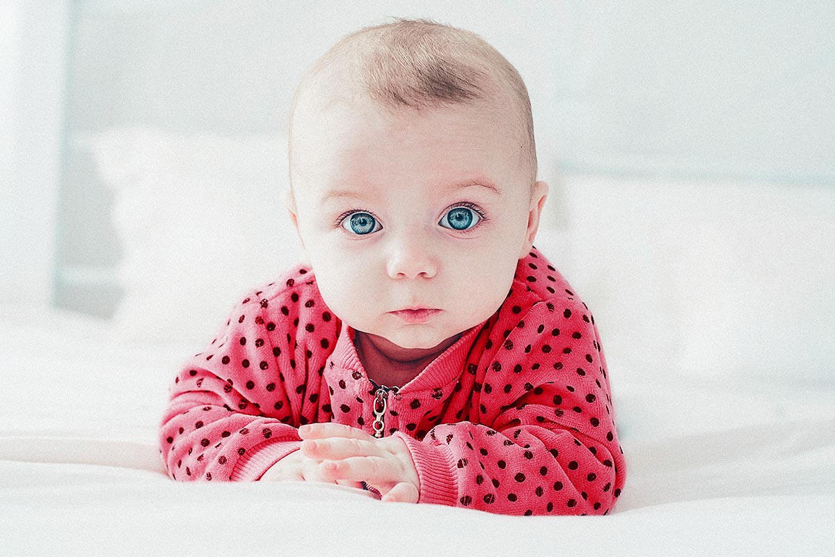 baby with blue eyes and a pink outfit with black polka dots