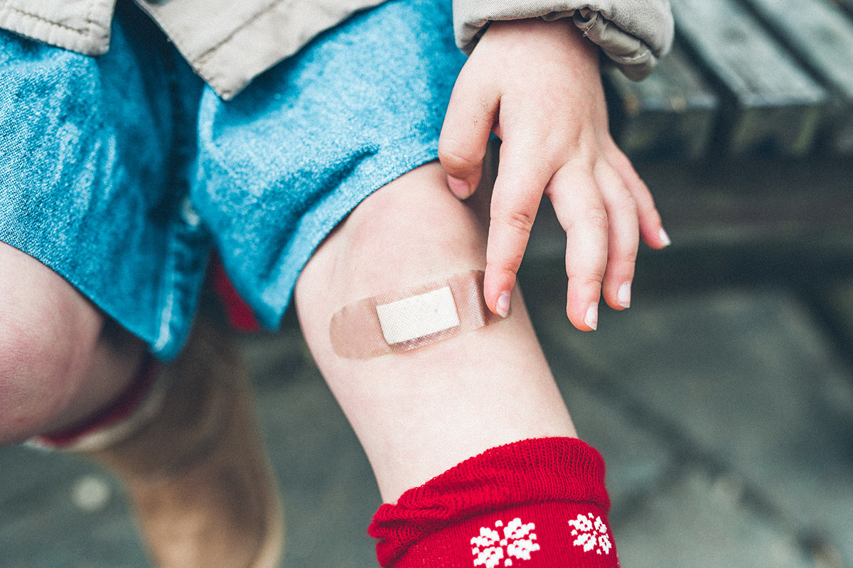 kid putting a band aid on their leg