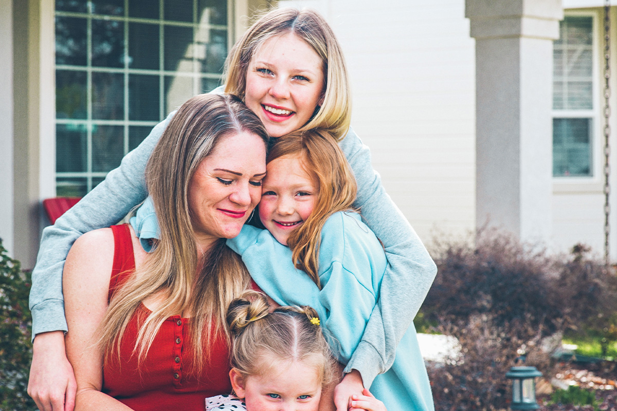 three daughters hugging their mom