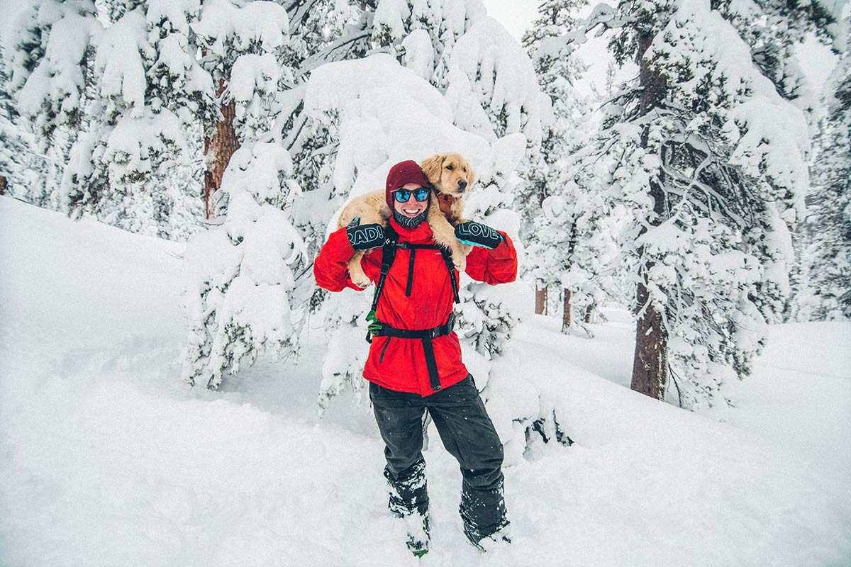 Andrew Muse in the snow holding a dog over his shoulders