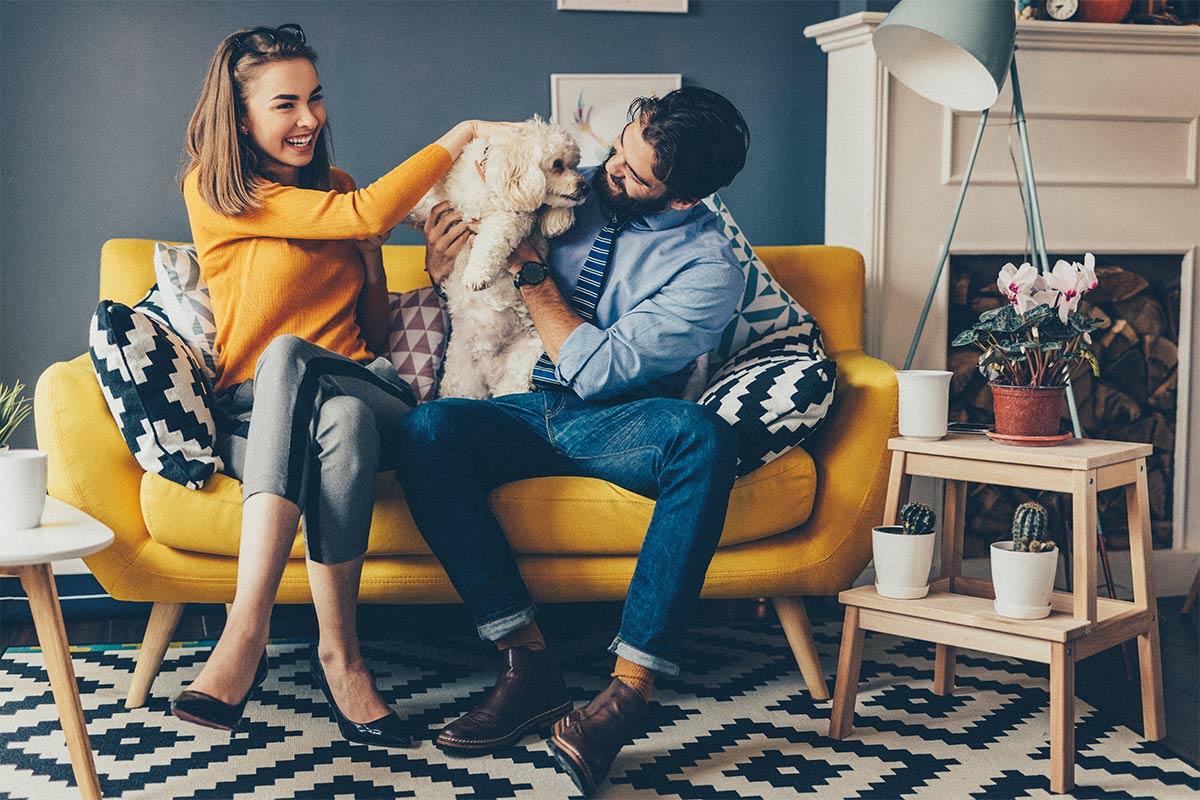 couple sitting on a couch with their dog