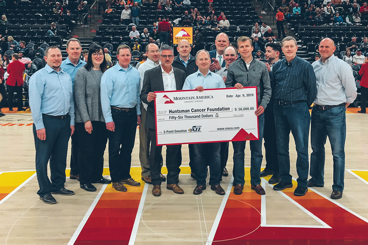 people holding a donation check on a basketball court