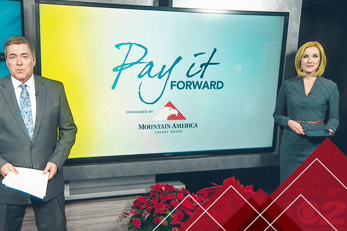 two people in front of a 'Pay it forward' sign