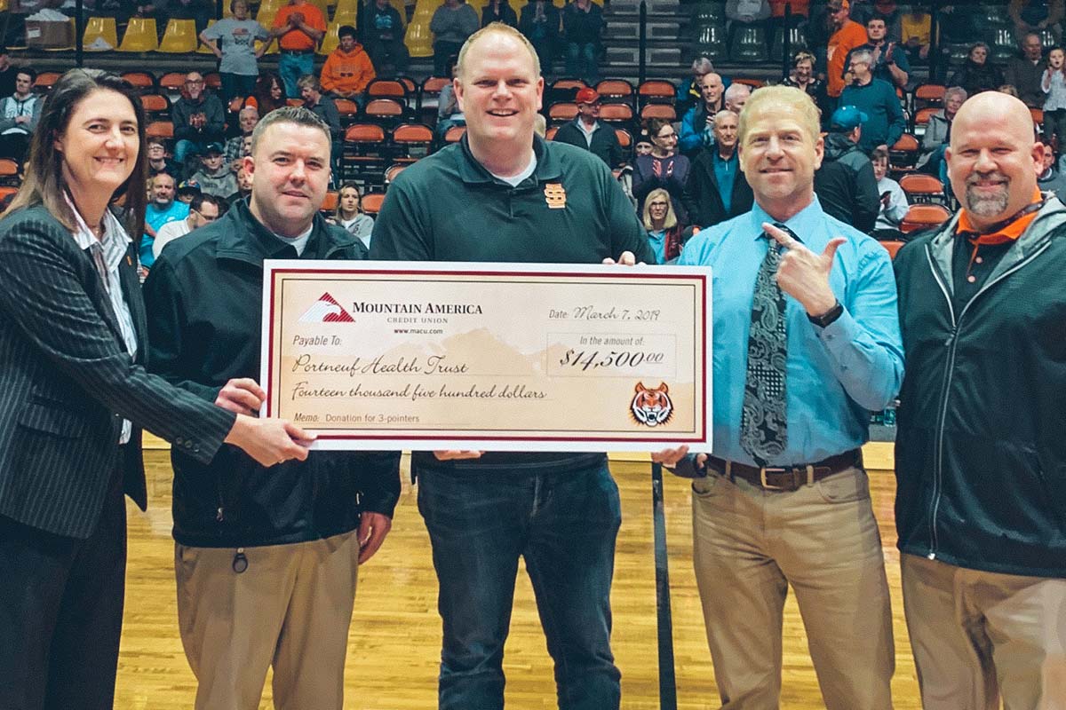 people holding a donation check on a basketball court