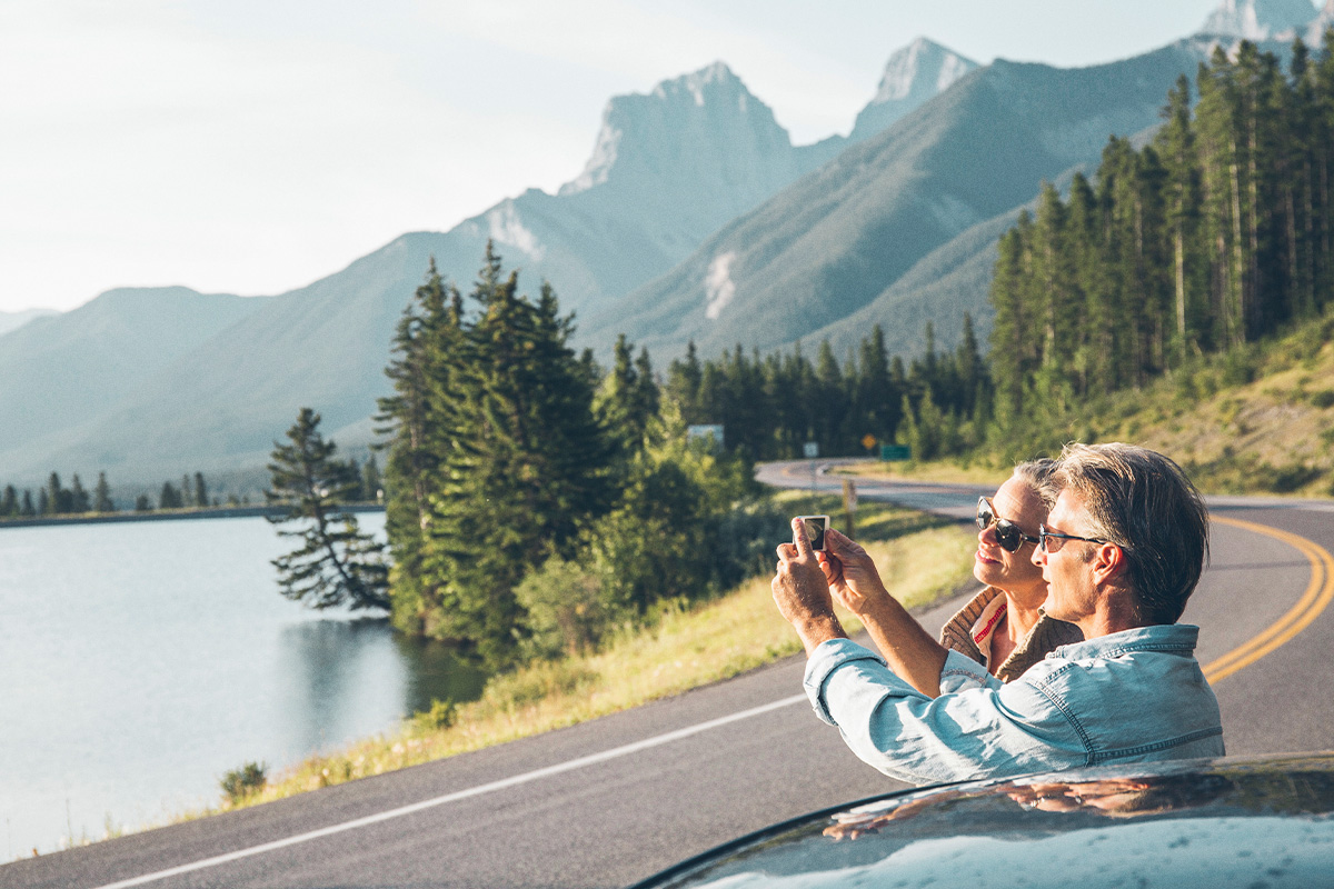 old couple taking a photo of mountain scenery