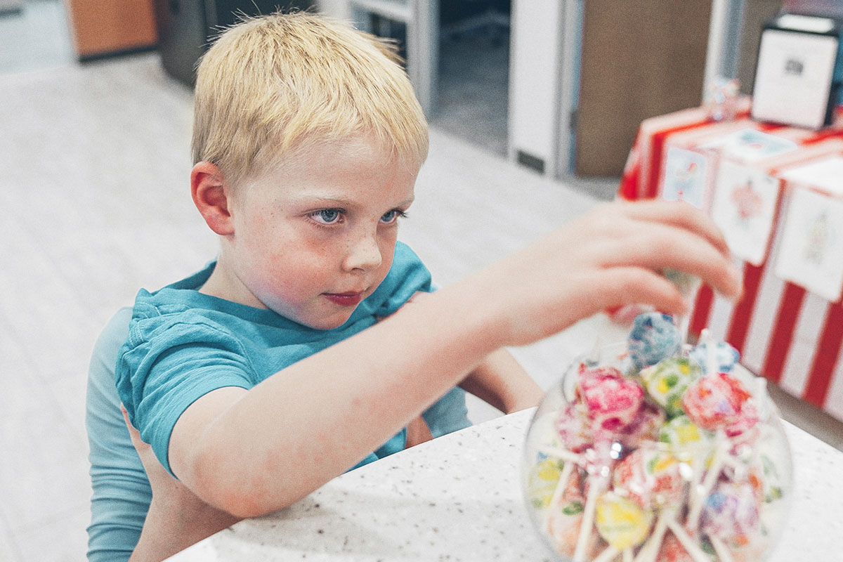 little boy grabbing a lollipop from a jar