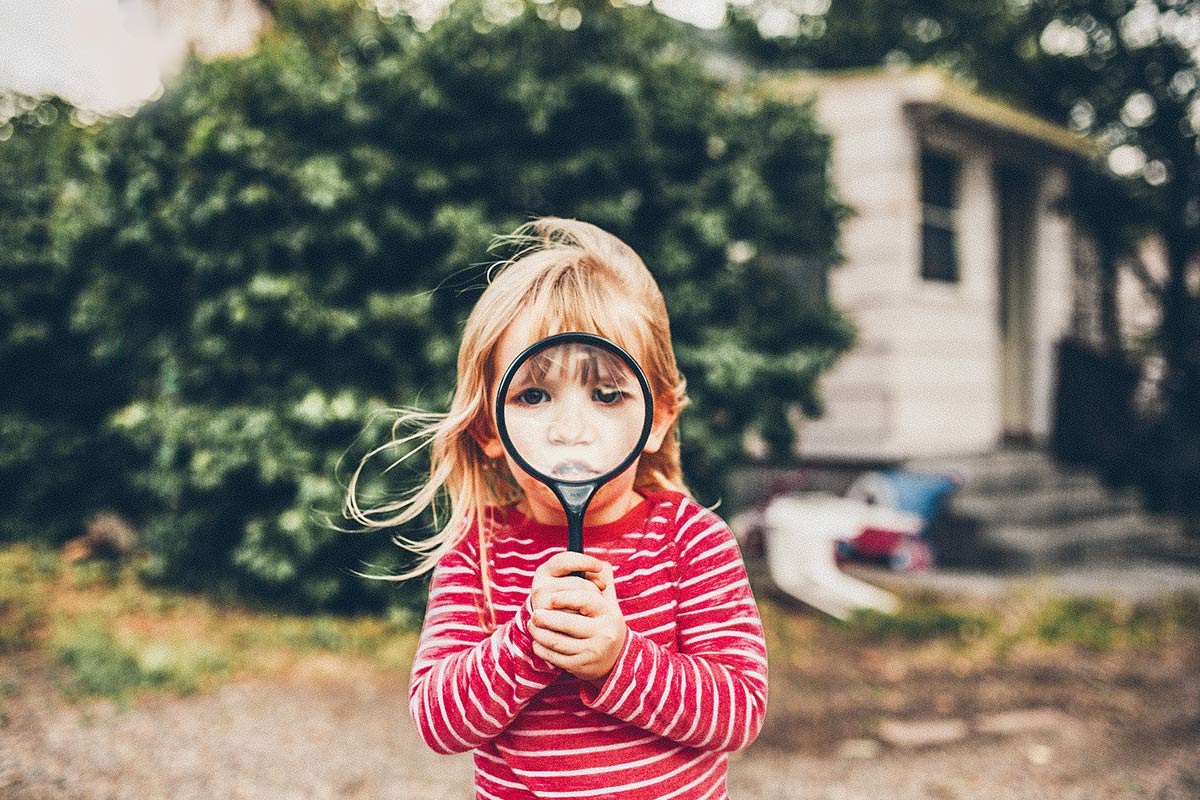 little girl looking through magnifying glass